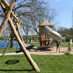 Kinderen spelen op een speeltuin met glijbaan en schommels in vakantiepark Beloofde Land, Gelderland.