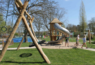 Bambini giocano su un parco giochi con scivolo e altalene a Beloofde Land, Gelderland, Paesi Bassi.