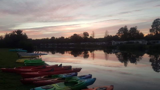 Kayaks alineados junto a un lago al atardecer en Camping de Kleine Wielen, parque vacacional en Frisia, Países Bajos.