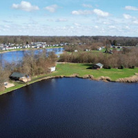 Vista aérea de un lago y zona verde cerca de Leeuwarden, Frisia, Países Bajos, con casas y árboles alrededor.