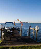 Ein dekorierter Holzsteg mit Booten am Wasser bei Voorthuizen, Gelderland, Niederlande, unter blauem Himmel.