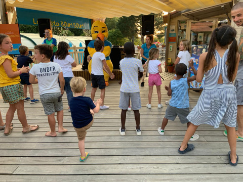 Kinder nehmen an einer unterhaltsamen Aktivität mit Maskottchen im Camping Paradis La Bretonniere in Frankreich teil.