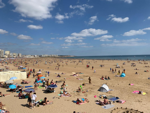 Busy beach scene at Camping Paradis La Bretonniere holiday park in Pays de la Loire, France, on a sunny day.