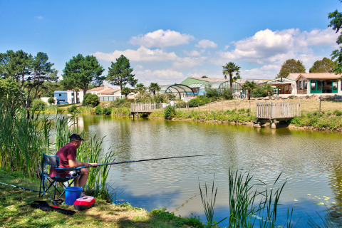 Hombre pescando junto a un estanque en Camping Paradis La Bretonniere, Pays de la Loire, Francia.