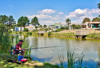 Mann angelt an einem Teich im Camping Paradis La Bretonniere, Pays de la Loire, Frankreich, bei Sonne.