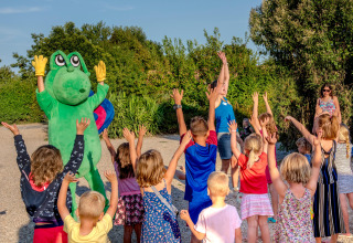 Kinderen spelen buiten met een persoon in een kikkerpak op Camping Paradis La Bretonniere, Pays de la Loire, Frankrijk.