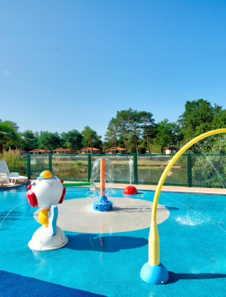 Piscina infantil y parque acuático con juegos de agua y tumbonas en Camping Paradis La Bretonniere, Pays de la Loire.