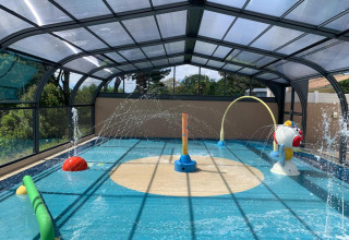 Überdachter Wasserspielplatz mit bunten Wasserspielen im Ferienpark Camping Paradis La Bretonniere, Frankreich.