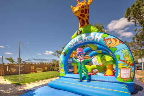 Hüpfburg mit Giraffe und Clown im Camping le Mas de Mourgues, Occitanie, Frankreich, an einem sonnigen Tag.