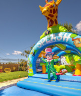 Parque inflable con jirafa y payaso en Camping le Mas de Mourgues, Occitanie, Francia, en un día soleado.