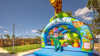 Hüpfburg mit Giraffe und Clown im Camping le Mas de Mourgues, Occitanie, Frankreich, an einem sonnigen Tag.