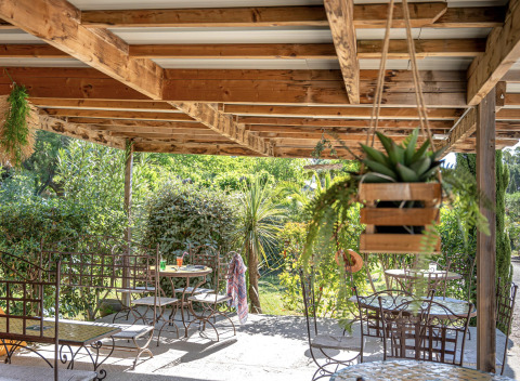 Shaded terrace with wrought iron furniture at Camping le Mas de Mourgues holiday park in Occitanie, France.