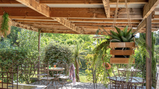 Überdachte Terrasse mit schmiedeeisernen Stühlen auf Camping le Mas de Mourgues in Occitanie, Frankreich.