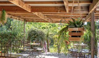 Terraza sombreada con muebles de hierro forjado en Camping le Mas de Mourgues, Occitanie, Francia.