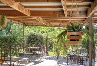 Shaded terrace with wrought iron furniture at Camping le Mas de Mourgues holiday park in Occitanie, France.