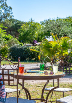 Tisch im Freien mit Getränken, Sonnenhut und Tuch im Camping le Mas de Mourgues in Occitanie, Frankreich.