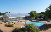 Udendørs swimmingpool og glashus omgivet af træer på Huttopia Saumur feriepark i Pays de la Loire, Frankrig.