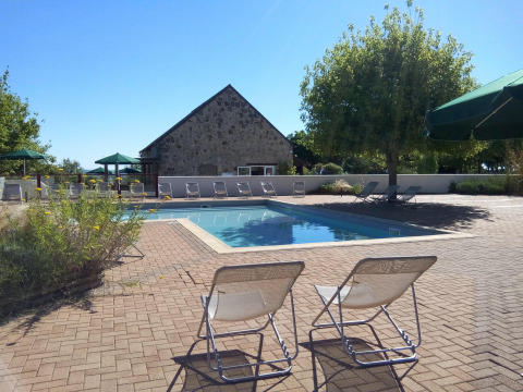 Área de piscina al aire libre con tumbonas en Huttopia Saumur, parque de vacaciones en Pays de la Loire, Francia.