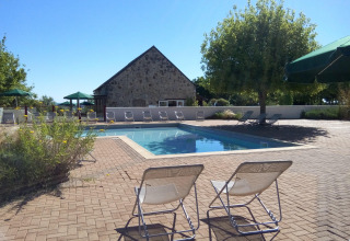 Outdoor pool area with lounge chairs at Huttopia Saumur holiday park in Pays de la Loire, France, on a sunny day.