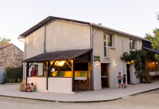 Vakantieparkgebouw bij Huttopia Saumur in Pays de la Loire, Frankrijk, met kinderen en volwassenen buiten.