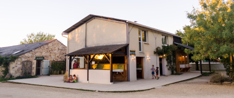 Bâtiment du parc de vacances Huttopia Saumur en Pays de la Loire, France, enfants jouant et gens profitant dehors.