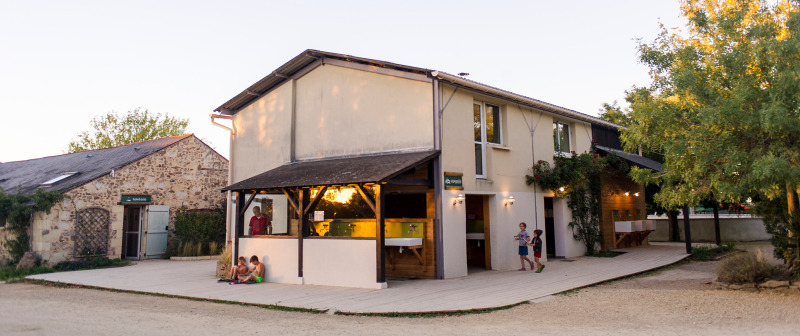 Vakantieparkgebouw van Huttopia Saumur in Pays de la Loire, Frankrijk, met kinderen en volwassenen buiten.