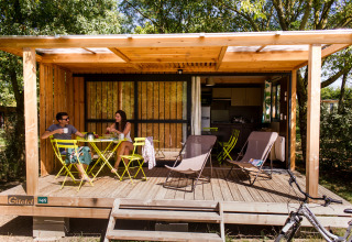 Twee personen genieten van ontbijt op het houten terras van een hut in Huttopia Saumur, Pays de la Loire, Frankrijk.
