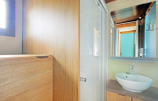 Moderne badeværelse i Chalet Evasion glamping, lyst træinteriør, vaskeskål og stort spejl.