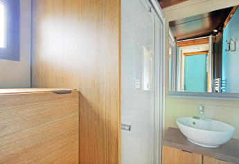 Moderne badeværelse i Chalet Evasion glamping, lyst træinteriør, vaskeskål og stort spejl.