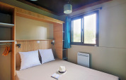 Habitación moderna de glamping en Chalet Evasion con cama doble, ventana, armario y decoración minimalista.