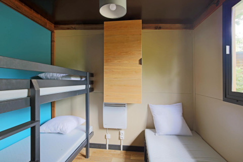 Habitación con litera y cama individual en Chalet Evasion glamping, decoración minimalista y ventana.