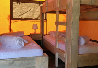 Interieur van een safaritent op Camping Paradis La Bretonnière in Frankrijk, met houten stapelbedden.