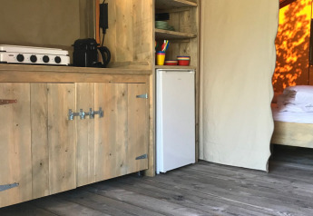 Innenaufnahme eines Safarizelts im Camping Paradis La Bretonniere mit Holzboden und Küche in Frankreich.