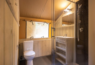 Modernes Badezimmer im Safarizelt Dreamer 49 mit Dusche, WC und Holzwaschtisch bei Arden Parks, Frankreich.