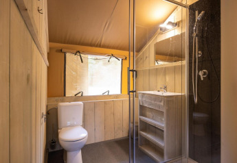 Modernes Badezimmer im Safarizelt Dreamer 49 mit Dusche, WC und Holzwaschtisch bei Arden Parks, Frankreich.