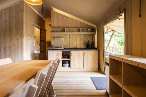 Vista interior de la tienda safari Dreamer 49 en Arden Parks - Signy l'Abbaye, Francia, con muebles de madera.