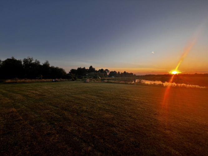 Zonsondergang boven een grasveld bij Camping de Beerte, een vakantiepark in Groningen, Nederland.