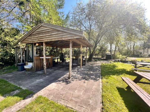 Überdachter Holzpavillon in Camping de Beerte, Groningen, Niederlande, umgeben von grüner Natur.