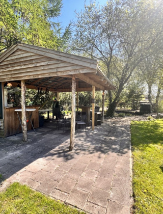 Pabellón de madera al aire libre en Camping de Beerte, Groningen, Países Bajos, rodeado de naturaleza.