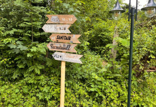 Houten bord met richtingen in Camping de Beerte, Groningen, Nederland, in een groene omgeving.