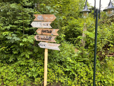 Houten bord met richtingen in Camping de Beerte, Groningen, Nederland, in een groene omgeving.