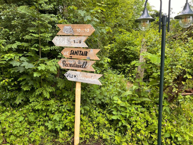 Holzwegweiser im Grünen bei Camping de Beerte, Groningen, Niederlande, mit holländischen Schildern.