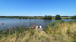Turistas se relajan junto al lago en Camping de Beerte, un parque vacacional en Groningen, Países Bajos.