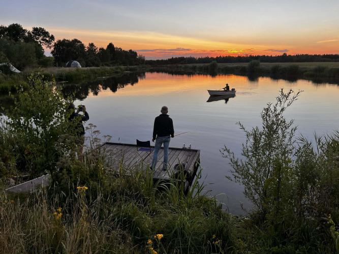 Zonsondergang bij een meer nabij Beerta, Groningen, Nederland, met mensen die vissen en roeien.