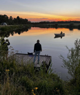 Atardecer en un lago cerca de Beerta, Groningen, Países Bajos, con personas pescando y remando en bote.