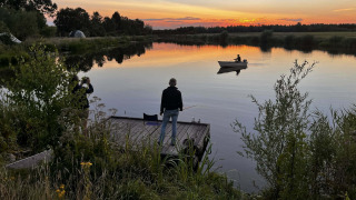 Atardecer en un lago cerca de Beerta, Groningen, Países Bajos, con personas pescando y remando en bote.