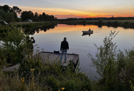 Atardecer en un lago cerca de Beerta, Groningen, Países Bajos, con personas pescando y remando en bote.