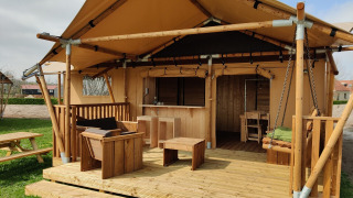 Safari-Glamping-Zelt mit Holzterrasse und Sitzgelegenheiten im Holiday Park Eigen Wijze in den Niederlanden.