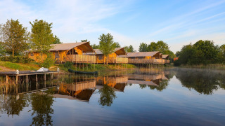 Tiendas glamping cómodas junto al lago en Holiday park Eigen Wijze, Países Bajos, rodeadas de árboles.