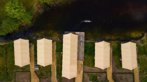 Luchtfoto van safaritenten en een kano op het water in vakantiepark Eigen Wijze, Flevoland, Nederland.